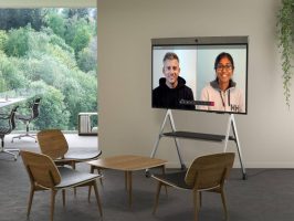 Neat Board mit mobiler Neat Bar auf Geräteständer – Videokonferenz in entspannter Lounge-Umgebung mit zwei Teilnehmenden