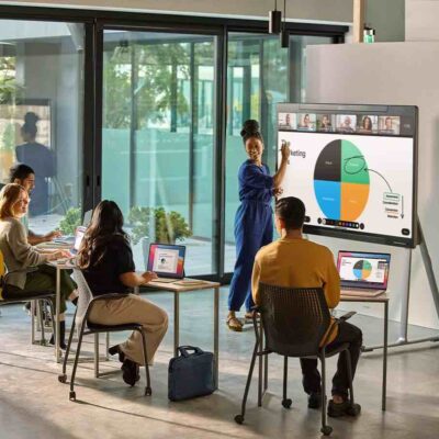 Schulungs- oder Unterrichtssituation mit Cisco Board Pro: Eine Lehrkraft erklärt Inhalte auf einem interaktiven Whiteboard, während Lernende mit digitalen Geräten arbeiten.