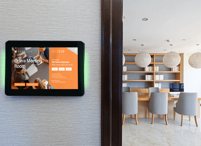 Ein Raumbuchungsterminal mit TEOS Software zeigt die aktuelle Belegung und Verfügbarkeit eines Meetingraums an – installiert an der Wand eines modernen Bürogebäudes, ideal für hybride Arbeitsplatzmodelle und effiziente Raumverwaltung.